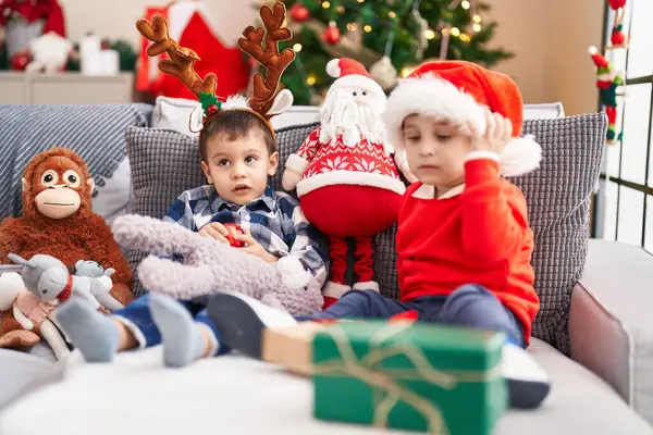 Två Barn Som Håller Bollen Sittandes Soffan Vid Julgranen Hemma — Stockfoto
