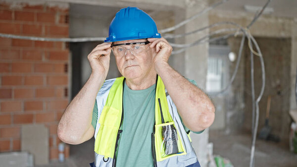 Middle age grey-haired man builder smiling confident wearing glasses at construction site