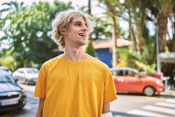 Young blond man smiling confident looking to the side at street