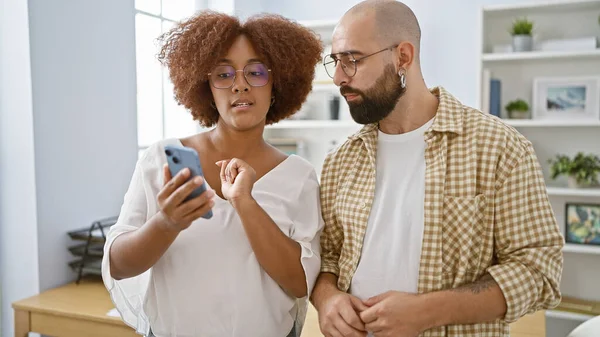 2人の集中した労働者 1人の男性と1人の女性は ビジネスの成功に集中しながら オフィスでスマートフォンで一緒に働いています — ストック写真