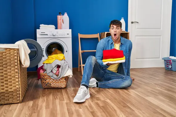 Jovem Hispânico Segurando Roupa Limpa Com Medo Chocado Com Expressão — Fotografia de Stock