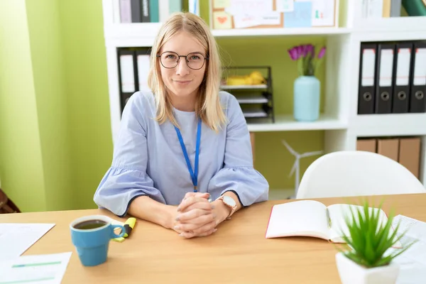 Young blonde woman business worker smiling confident sitting on table at office
