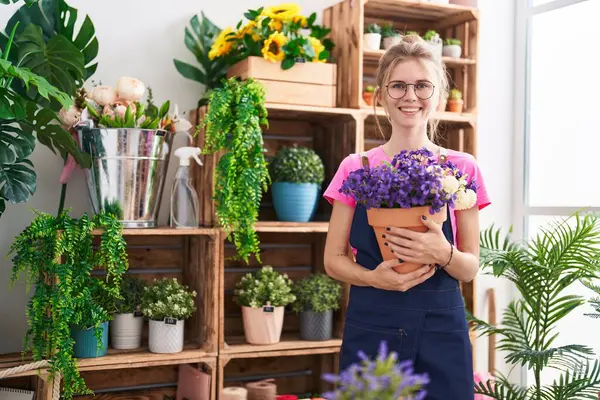 Joven Florista Mujer Rubia Sonriendo Con Confianza Celebración Planta Florería —  Fotos de Stock