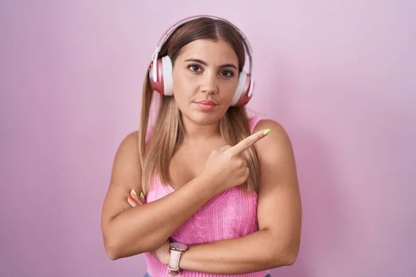 Mladá Blondýnka Poslouchající Hudbu Pomocí Sluchátek Ukazující Ukazováčkem Stranu Ukazující — Stock fotografie