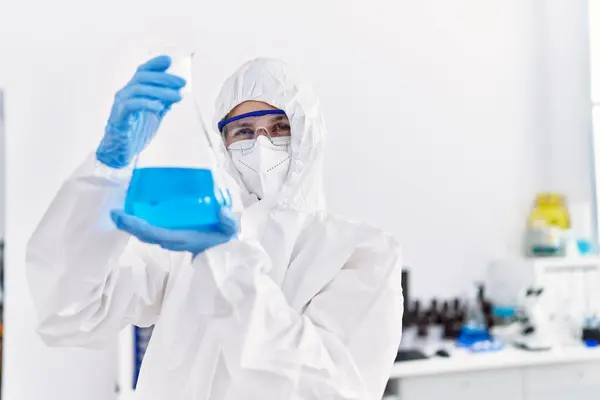 Young blonde woman scientist wearing security uniform holding test tube at laboratory