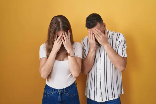 Sarı Arka Planda Dikilen Genç Çift Ağlarken Yüzlerini Ellerle Kapatıyor — Stok fotoğraf