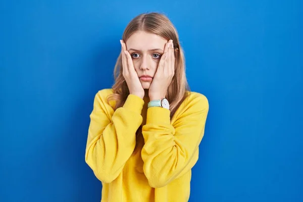 stock image Young caucasian woman standing over blue background tired hands covering face, depression and sadness, upset and irritated for problem 