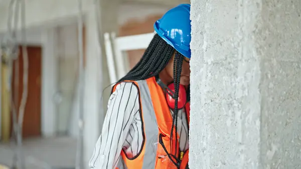 African american woman builder stressed hitting wall with head at construction site