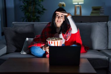 İspanyol kadın kanepede film seyrederek patlamış mısır yiyor. Çok mutlu ve gülümsüyor. Çok uzaklara bakıyor. arama kavramı. 