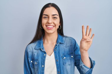 Mavi arka planda dikilen İspanyol kadın dört numarayı gösterip işaret ederken kendinden emin ve mutlu bir şekilde gülümsüyor.. 