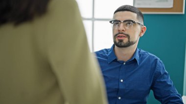 İki kendini işine adamış işçi, erkek ve kadın, çalışma masalarında ciddi bir iş tartışmasına giriştiler - profesyonel başarının açık bir ifadesi.