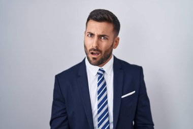 Yakışıklı, takım elbiseli ve kravatlı, şaşkın bakışlı, şüpheci ve alaycı, ağzı açık kalmış. 