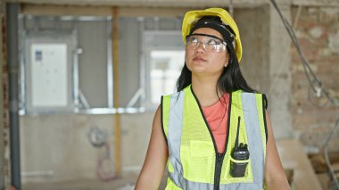 Ciddi yüzlü genç Çinli mimar inşaat alanına bakıyor.