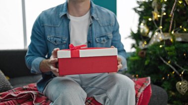 Genç İspanyol adam Noel hediyesini evde tutuyor.