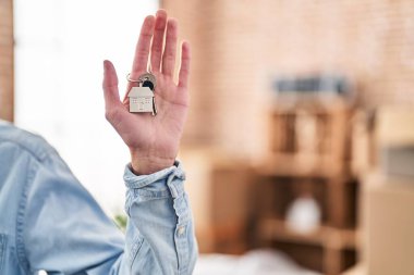 Young hispanic man holding key at new home