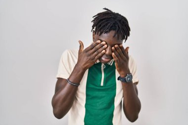 Rastalı Afrikalı bir adam arka planda duruyor yorgunluk ve baş ağrısı için gözlerini ovuşturuyor, uykulu ve yorgun bir ifade takınıyor. görme sorunu 