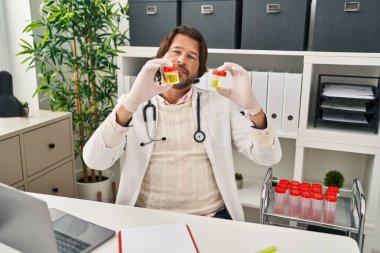 Klinikte idrar tüpleri tutan orta yaşlı bir doktor.