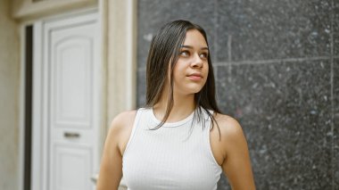Young beautiful hispanic woman looking to the side with serious expression at street