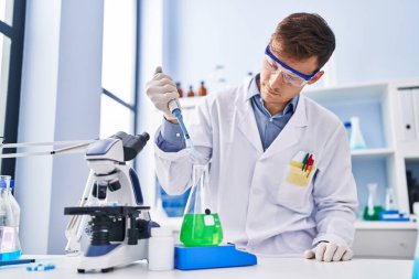 Laboratuvarda test tüpüne sıvı döken genç bir bilim adamı.