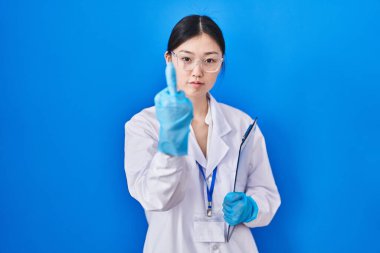 Chinese young woman working at scientist laboratory showing middle finger, impolite and rude fuck off expression 