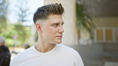 Genç, yakışıklı, beyaz, sakin ama ciddi bir yüz ifadesi sergiliyor, açık havada güneşli bir havada dikilirken yan tarafa bakıyor. Sokak modası şehir ve havalı yaşam tarzını gözler önüne seriyor.