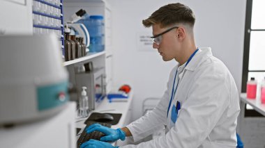 Çekici, beyaz erkek bilim adamı test tüpleri ve mikroskoplar arasında bilgisayara kendini tamamen kaptırmış durumda.