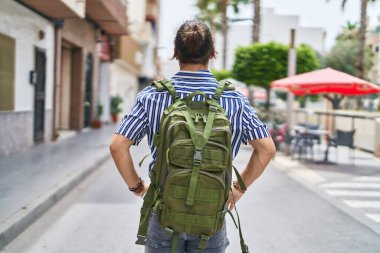 Young hispanic man tourist wearing backpack walking at street