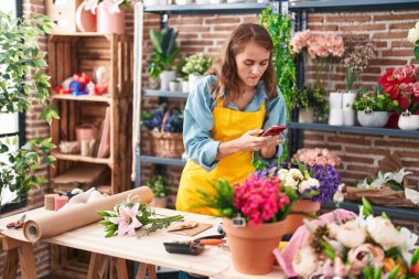 Genç, güzel, İspanyol bir çiçekçi çiçekçiye akıllı telefondan fotoğraf dikmiş.