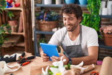 Çiçekçide dokunmatik ped kullanarak gülümseyen İspanyol çiçekçi.