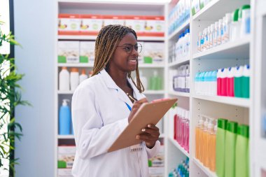 Afrika kökenli Amerikalı kadın eczacı eczanedeki belgeye yazı yazıyor.