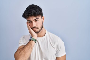 Hispanic man with beard standing over white background thinking looking tired and bored with depression problems with crossed arms. 