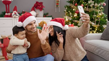 Bir çift ve oğlu evdeki Noel ağacının yanında otururken görüntülü konuşma yapıyorlar.