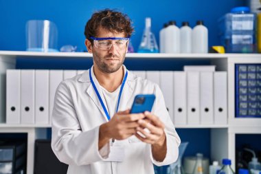 Young man scientist using smartphone at laboratory