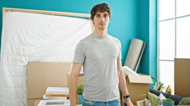 Yeni evinde ciddi yüzüyle duran Latin asıllı genç adam.