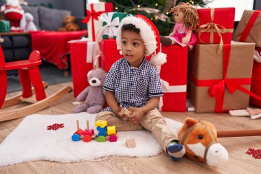 Afrikalı Amerikalı çocuk evde Noel ağacının yanında oyuncakla oynuyor.