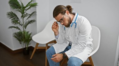 Klinikteki bekleme odasında sandalyede oturan genç İspanyol doktor.