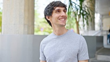 Young hispanic man smiling confident looking to the side at street