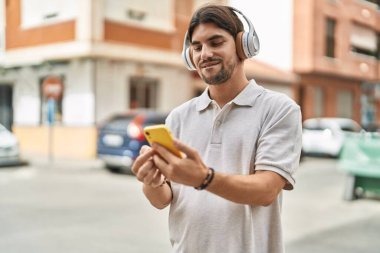 Sokakta müzik dinlerken kendinden emin gülümseyen İspanyol genç adam.