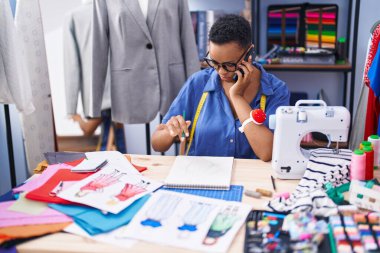 Afro-Amerikalı kadın terzi, terzi dükkanında akıllı telefondan çizim yapıyor.