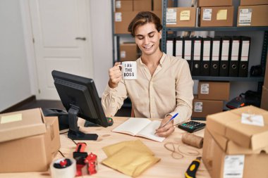 Young caucasian man ecommerce business worker writing on notebook drinking coffee at office