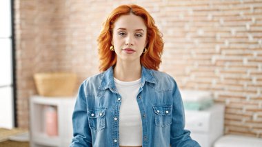 Çamaşır odasında rahat bir ifadeyle duran genç kızıl saçlı kadın.