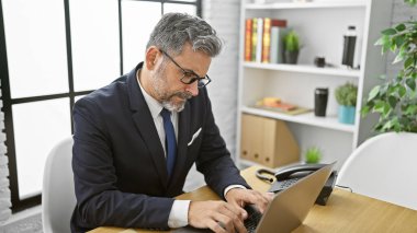 Çekici, gri saçlı, genç İspanyol bir adam, zarif bir profesyonel, ofiste sıkı konsantre oluyor. Ciddi bir şekilde çalışıyor. Masasındaki bilgisayarından iş başarısını yönetiyor..