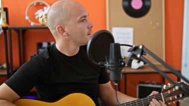 Young hispanic man musician singing song playing classical guitar at music studio