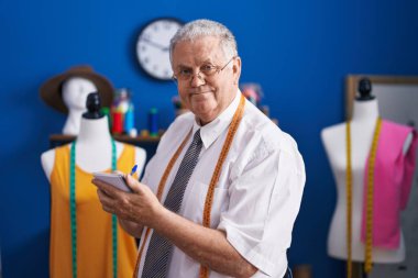 Orta yaşlı, gri saçlı, terzi dükkanında kendine güvenen, kendine güvenen bir terzi.