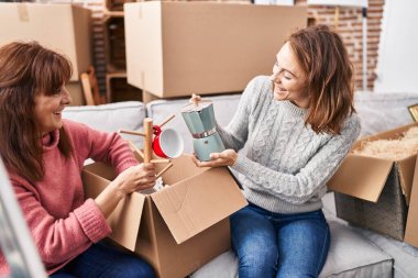 Two women mother and daughter unpacking cardboard box at street