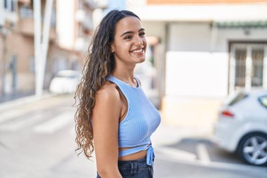 Young beautiful hispanic woman smiling confident looking to the side at street