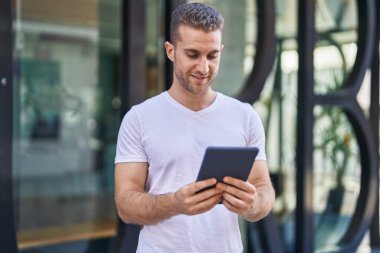 Young caucasian man smiling confident using touchpad at street