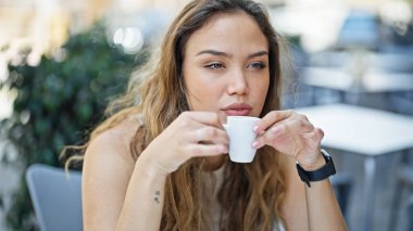 Genç ve güzel İspanyol kadın kahve dükkanının terasında oturmuş kahve içiyor.