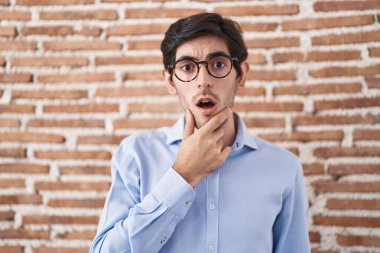 Duvarın arkasında dikilen Latin asıllı genç adam elleri çenesinde olan inançsızlıktan, şaşkınlıktan ve şaşkınlıktan büyülenmiş görünüyor. 