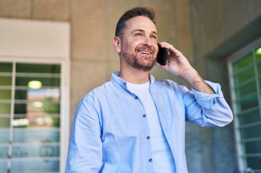 Kafkasyalı genç adam gülümsüyor. Kendine güvenen caddedeki akıllı telefondan konuşuyor.